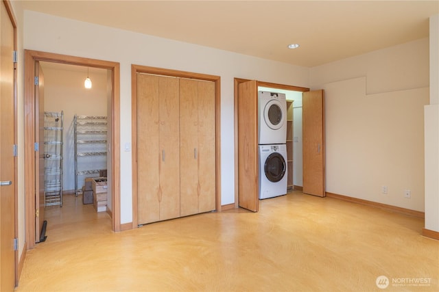 laundry room with laundry area, stacked washer / dryer, and baseboards