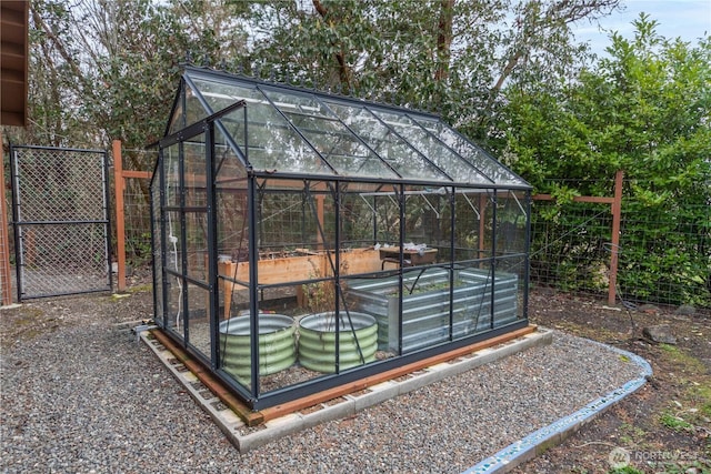 view of greenhouse featuring a gate and fence