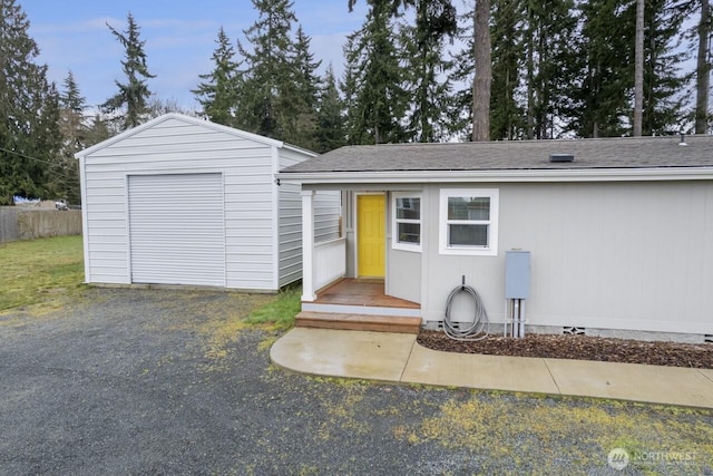 view of front of home featuring an outdoor structure, fence, roof with shingles, and crawl space