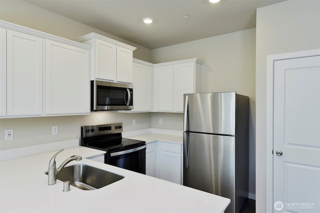 kitchen featuring a sink, appliances with stainless steel finishes, white cabinets, and light countertops