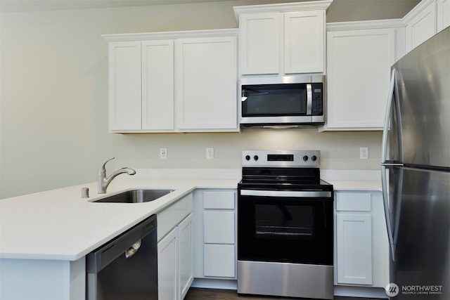 kitchen featuring a peninsula, a sink, light countertops, white cabinets, and appliances with stainless steel finishes