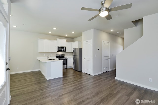 kitchen featuring dark wood finished floors, light countertops, a peninsula, stainless steel appliances, and a sink