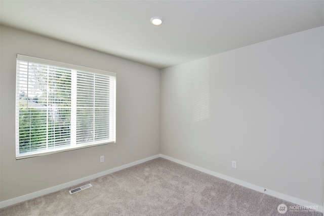 carpeted empty room featuring visible vents, a healthy amount of sunlight, and baseboards