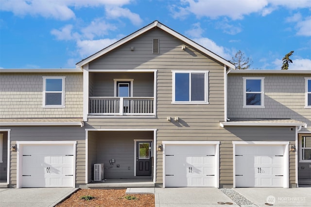 view of property with central air condition unit, a balcony, a garage, and driveway