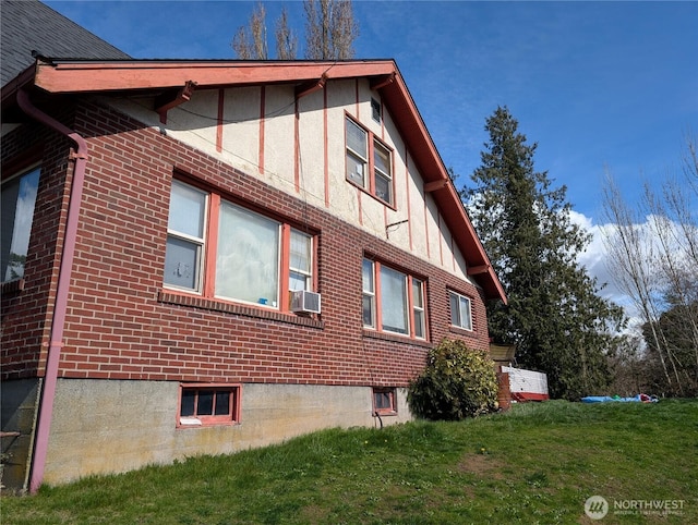 view of property exterior with cooling unit, brick siding, and a yard