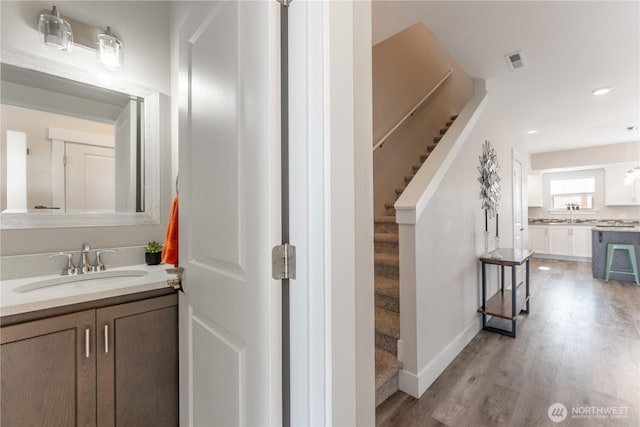 interior space with visible vents, vanity, baseboards, and wood finished floors