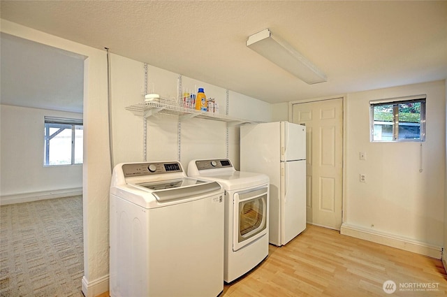 laundry area featuring laundry area, baseboards, light wood-type flooring, and washer and clothes dryer