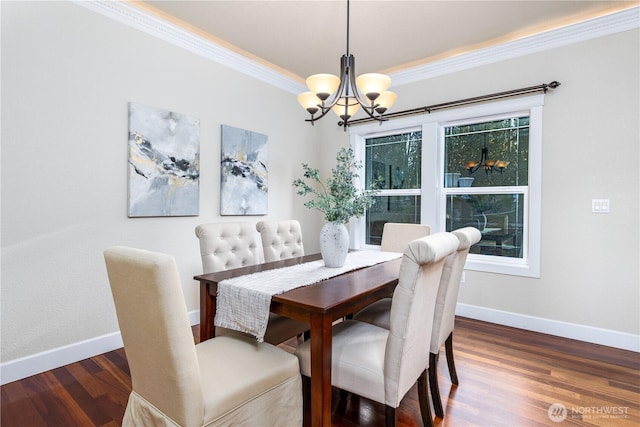 dining space with a chandelier, crown molding, baseboards, and wood finished floors