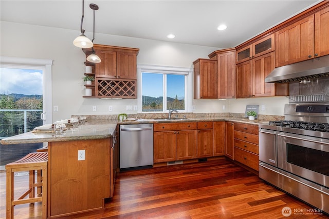 kitchen with under cabinet range hood, brown cabinets, appliances with stainless steel finishes, and a peninsula