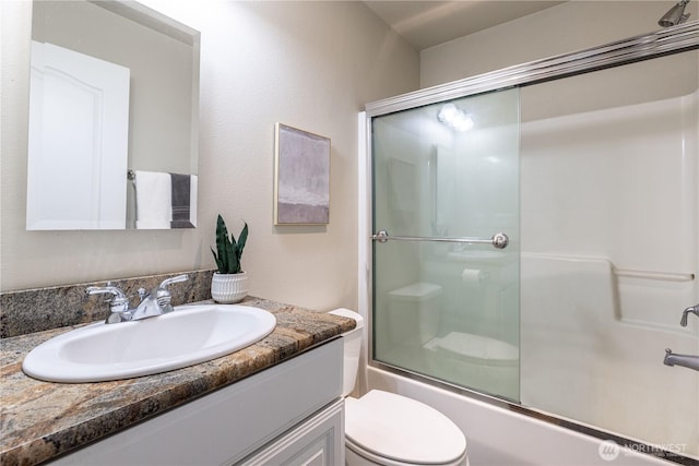 full bathroom featuring toilet, vanity, and shower / bath combination with glass door