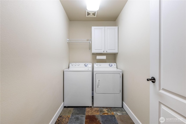 washroom with visible vents, stone finish floor, cabinet space, baseboards, and washing machine and clothes dryer