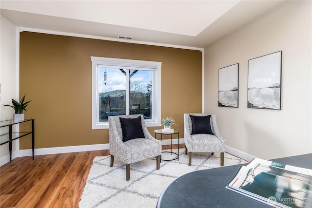 living area featuring wood finished floors, visible vents, and baseboards