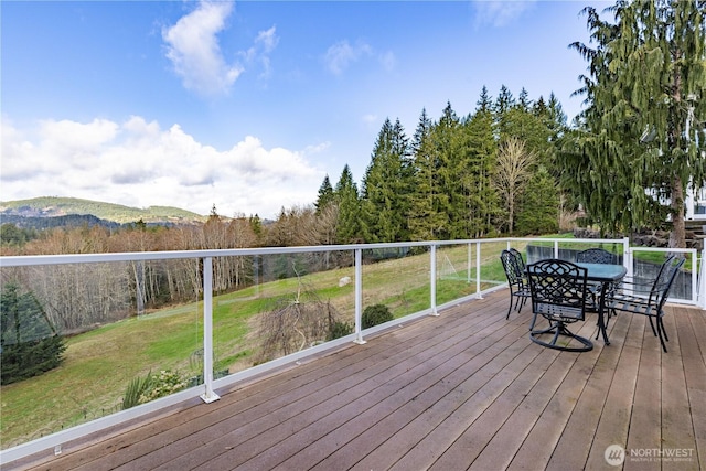 wooden deck featuring outdoor dining space and a yard