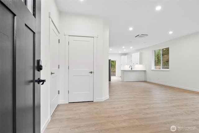 hall featuring light wood-style flooring, recessed lighting, visible vents, and baseboards