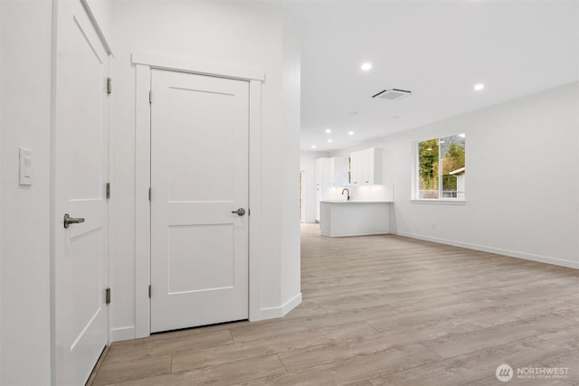 corridor with visible vents, a sink, recessed lighting, light wood-style floors, and baseboards