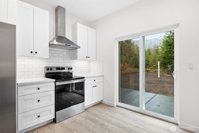 kitchen with wall chimney range hood, light countertops, electric range, and tasteful backsplash