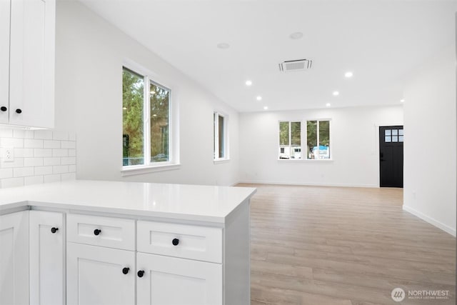 kitchen with decorative backsplash, a peninsula, visible vents, and a wealth of natural light