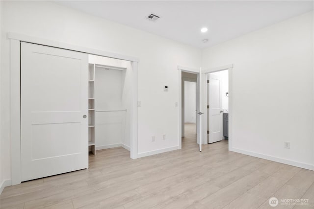 unfurnished bedroom featuring light wood-type flooring, visible vents, baseboards, and a closet