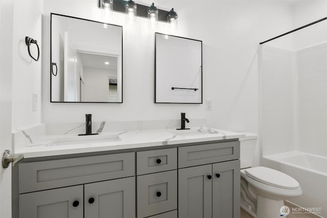 full bathroom featuring double vanity, toilet, bathing tub / shower combination, and a sink