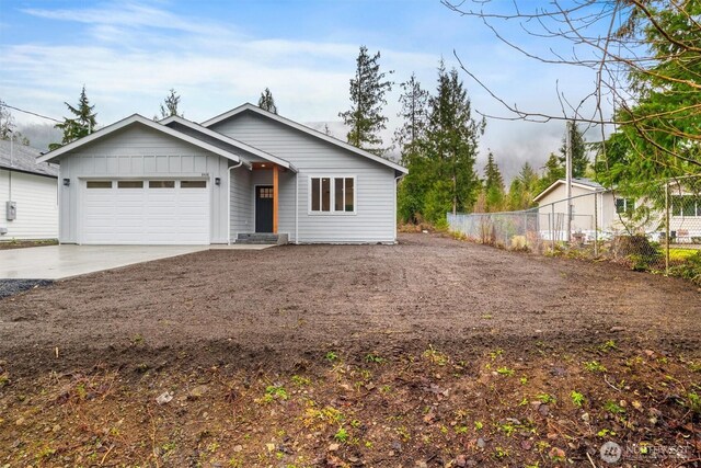 view of front of house with an attached garage, fence, board and batten siding, and driveway