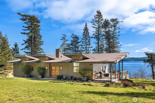 view of front of home with a chimney, a front lawn, french doors, a water view, and metal roof