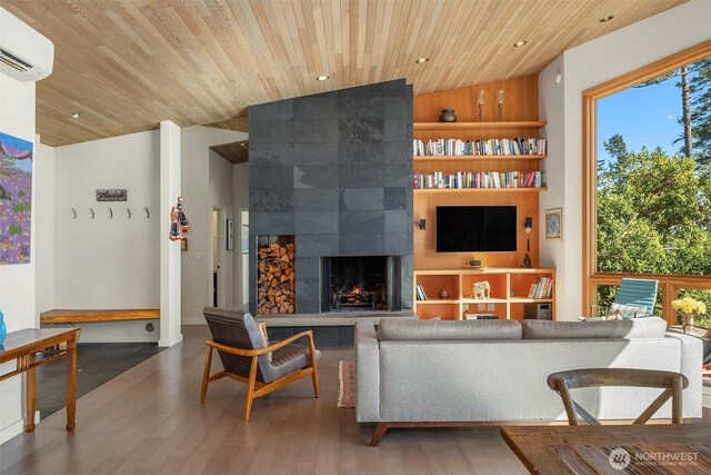 living room featuring wood finished floors, a wall unit AC, wooden ceiling, a fireplace, and lofted ceiling