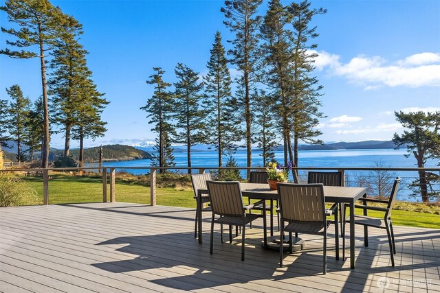 deck with a lawn, outdoor dining area, and a water view