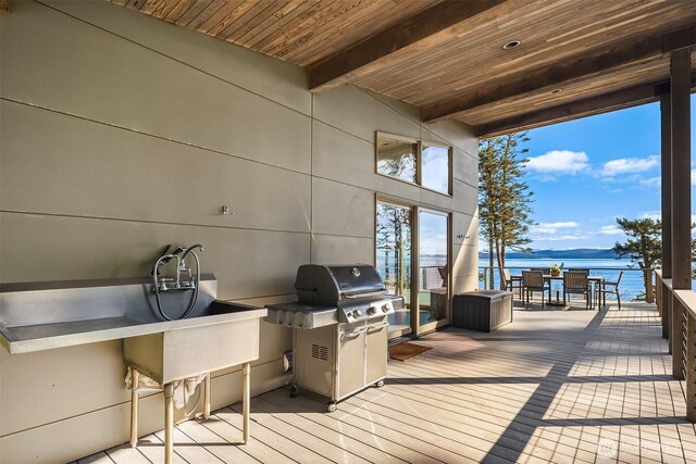 deck featuring a water view, a grill, and outdoor dining space