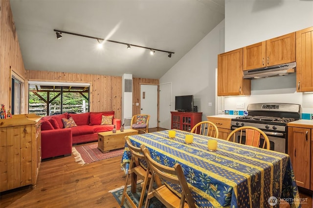kitchen with under cabinet range hood, open floor plan, gas range, and hardwood / wood-style flooring