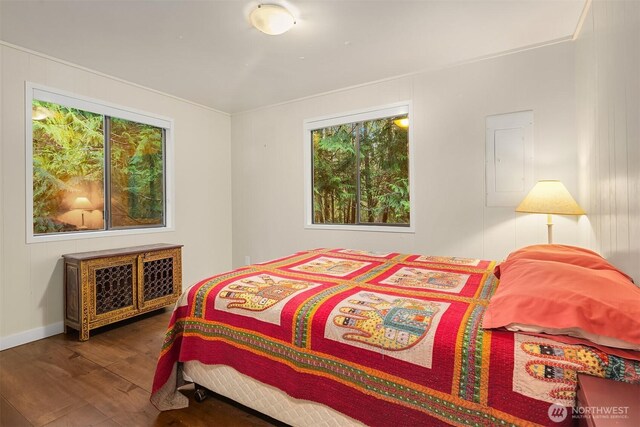 bedroom featuring electric panel, baseboards, and wood finished floors