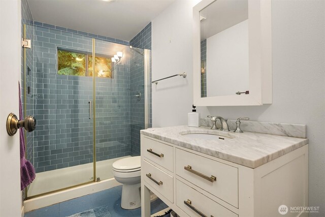 full bathroom with toilet, a stall shower, and vanity