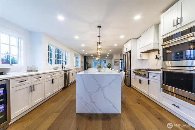 kitchen featuring beverage cooler, a kitchen island, custom exhaust hood, dark wood-type flooring, and appliances with stainless steel finishes