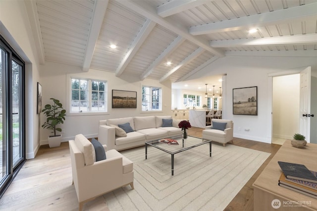 living area featuring vaulted ceiling with beams, light wood-style floors, and baseboards