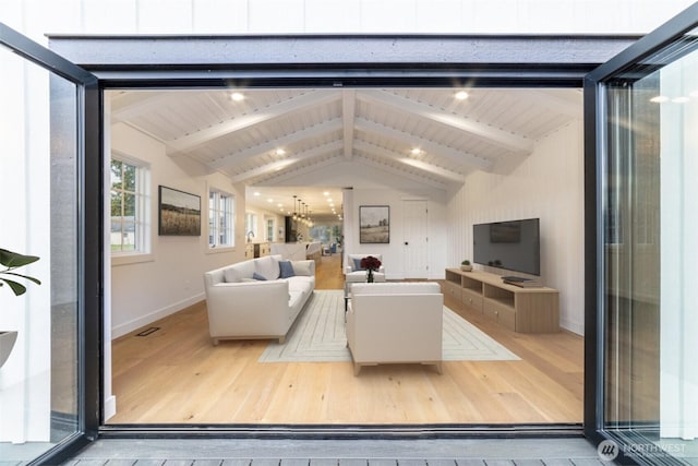 living area featuring visible vents, baseboards, hardwood / wood-style floors, and vaulted ceiling with beams