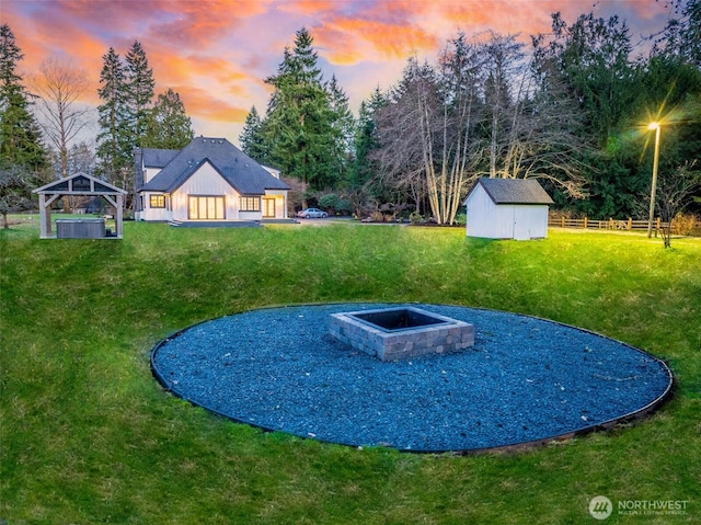 view of yard with fence, a gazebo, a fire pit, a storage shed, and an outdoor structure