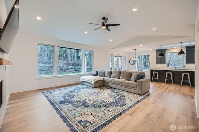 living room featuring light wood-type flooring, visible vents, a ceiling fan, recessed lighting, and vaulted ceiling