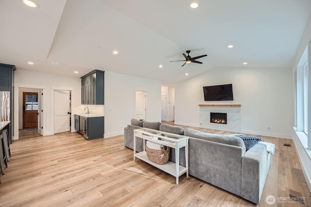 living room featuring a ceiling fan, a high end fireplace, recessed lighting, light wood-style floors, and lofted ceiling