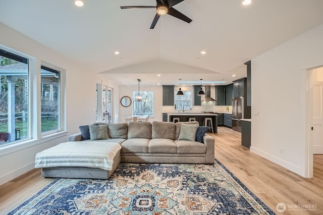 living room with vaulted ceiling, light wood-style flooring, baseboards, and ceiling fan