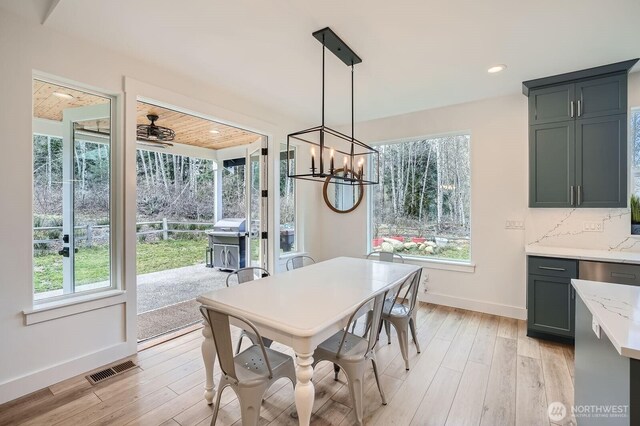 dining room with an inviting chandelier, baseboards, visible vents, and light wood-type flooring