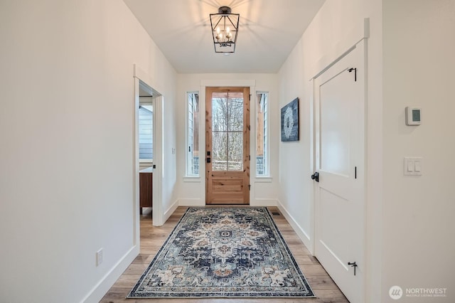 entrance foyer with baseboards, light wood-style floors, and a chandelier