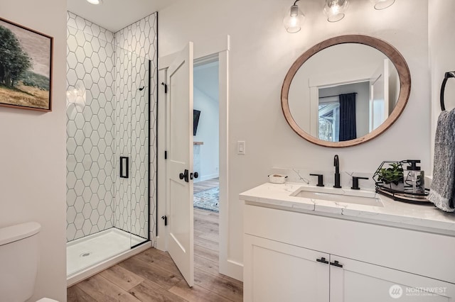 bathroom featuring vanity, a shower stall, toilet, and wood finished floors