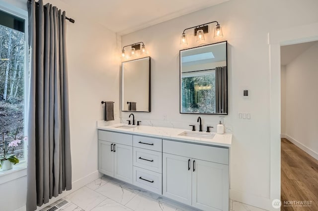 full bath featuring a sink, baseboards, marble finish floor, and double vanity