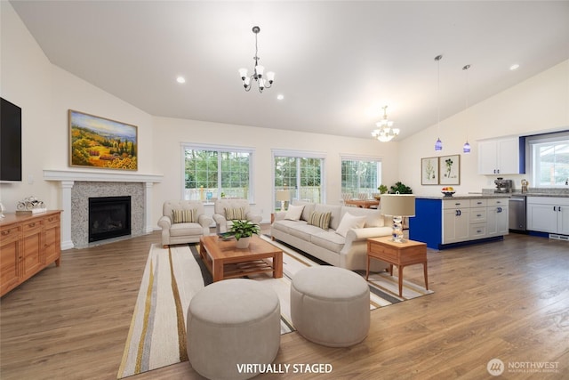 living room with light wood finished floors, a notable chandelier, and a healthy amount of sunlight