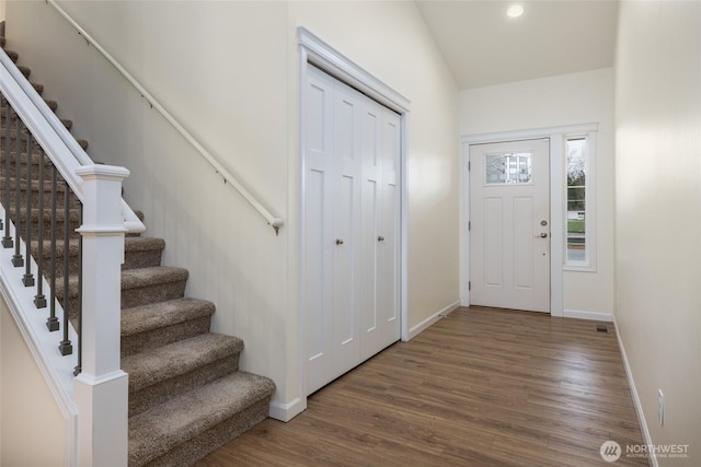 foyer entrance featuring baseboards, stairs, wood finished floors, and recessed lighting