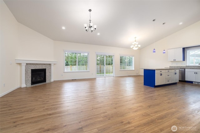 unfurnished living room with plenty of natural light, a notable chandelier, and light wood finished floors