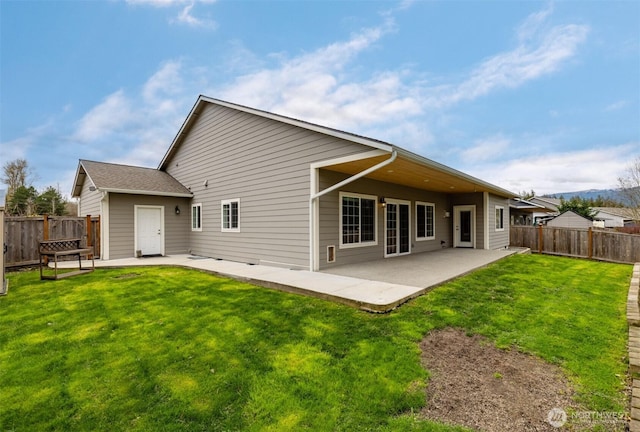 rear view of house featuring a fenced backyard, a lawn, and a patio