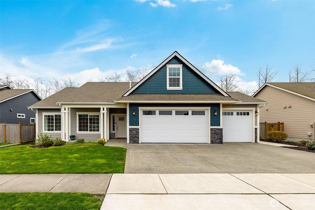 view of front of house featuring stone siding, aphalt driveway, fence, an attached garage, and a front lawn