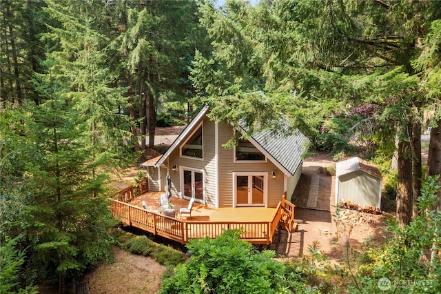 rear view of house with a forest view, french doors, metal roof, and a wooden deck