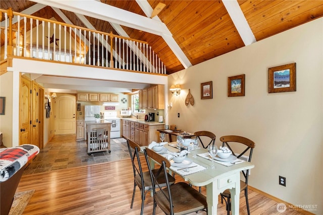 dining space with baseboards, light wood finished floors, high vaulted ceiling, wooden ceiling, and beamed ceiling