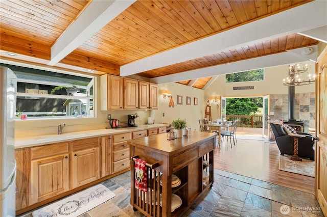 kitchen with a sink, plenty of natural light, stone tile flooring, and a wood stove